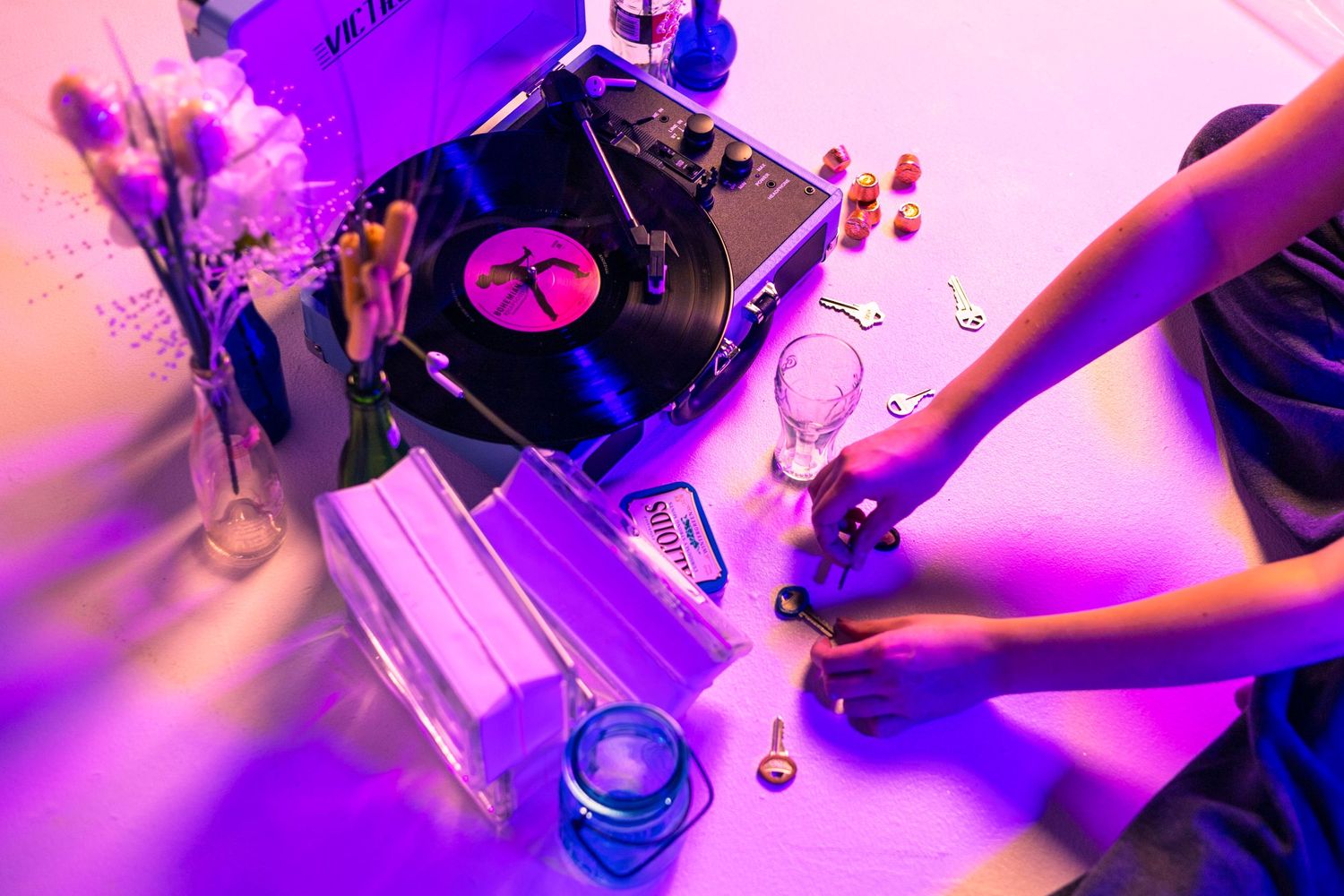 Close-up of turntable equipment bathed in pink and purple lighting.