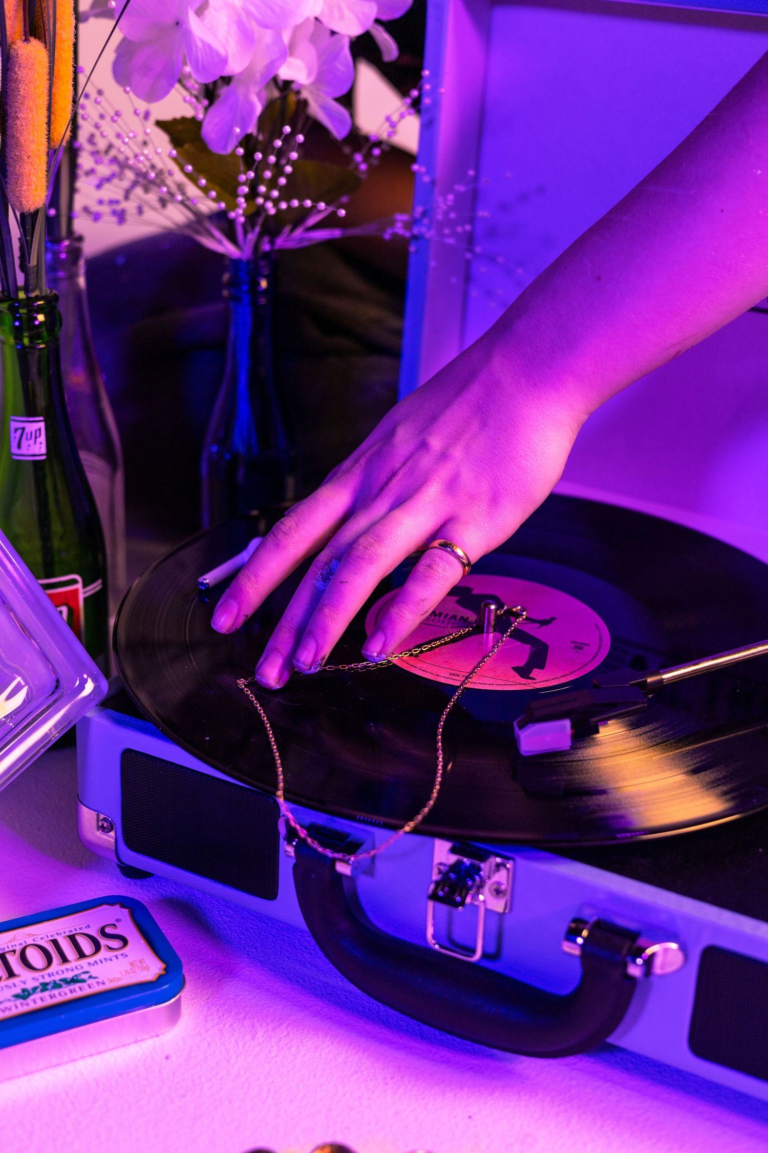 Vinyl record being placed on turntable under purple ambient lighting.