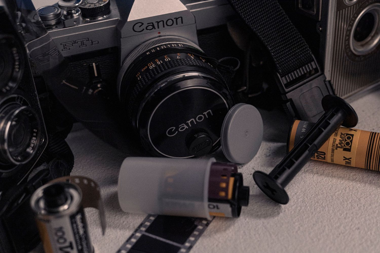 A classic Canon camera with lens and film strip displayed on white surface.