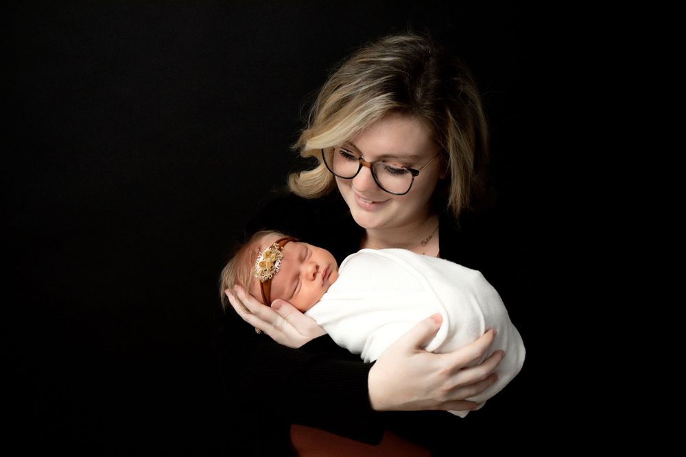 Heartwarming studio portrait showing a tender parent-child interaction against dark background.