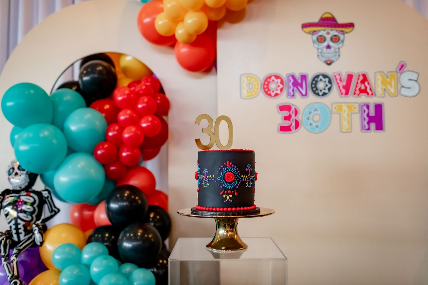 Festive birthday setup with colorful balloon garland and Day of the Dead themed decorations.
