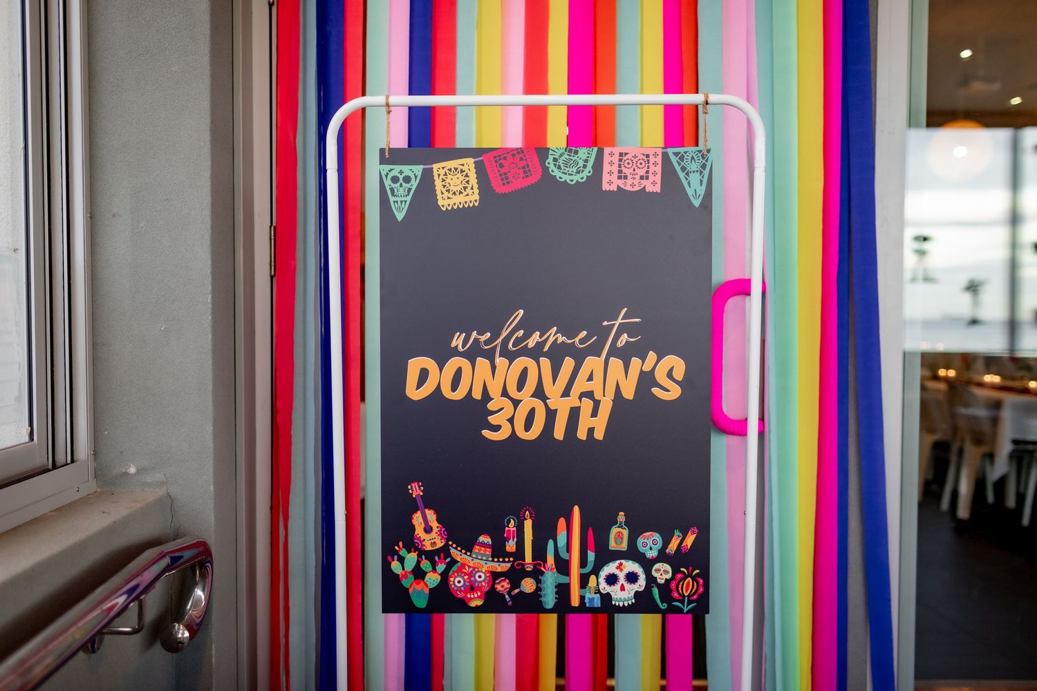 A dark party sign with rainbow stripes and neon city skyline design.