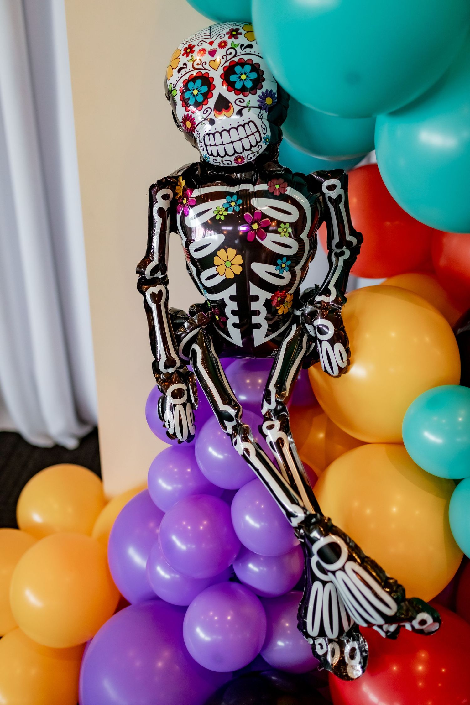 Decorative Day of the Dead skeleton balloon figure with colorful balloons in the background.