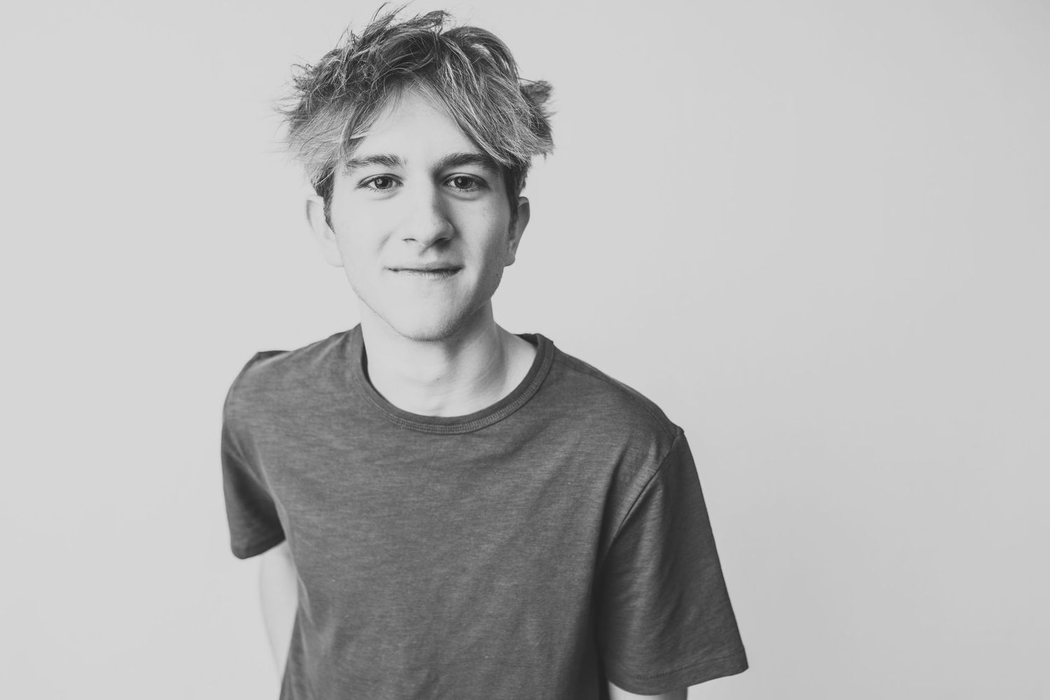Black and white portrait of someone in a casual t-shirt with tousled hair.