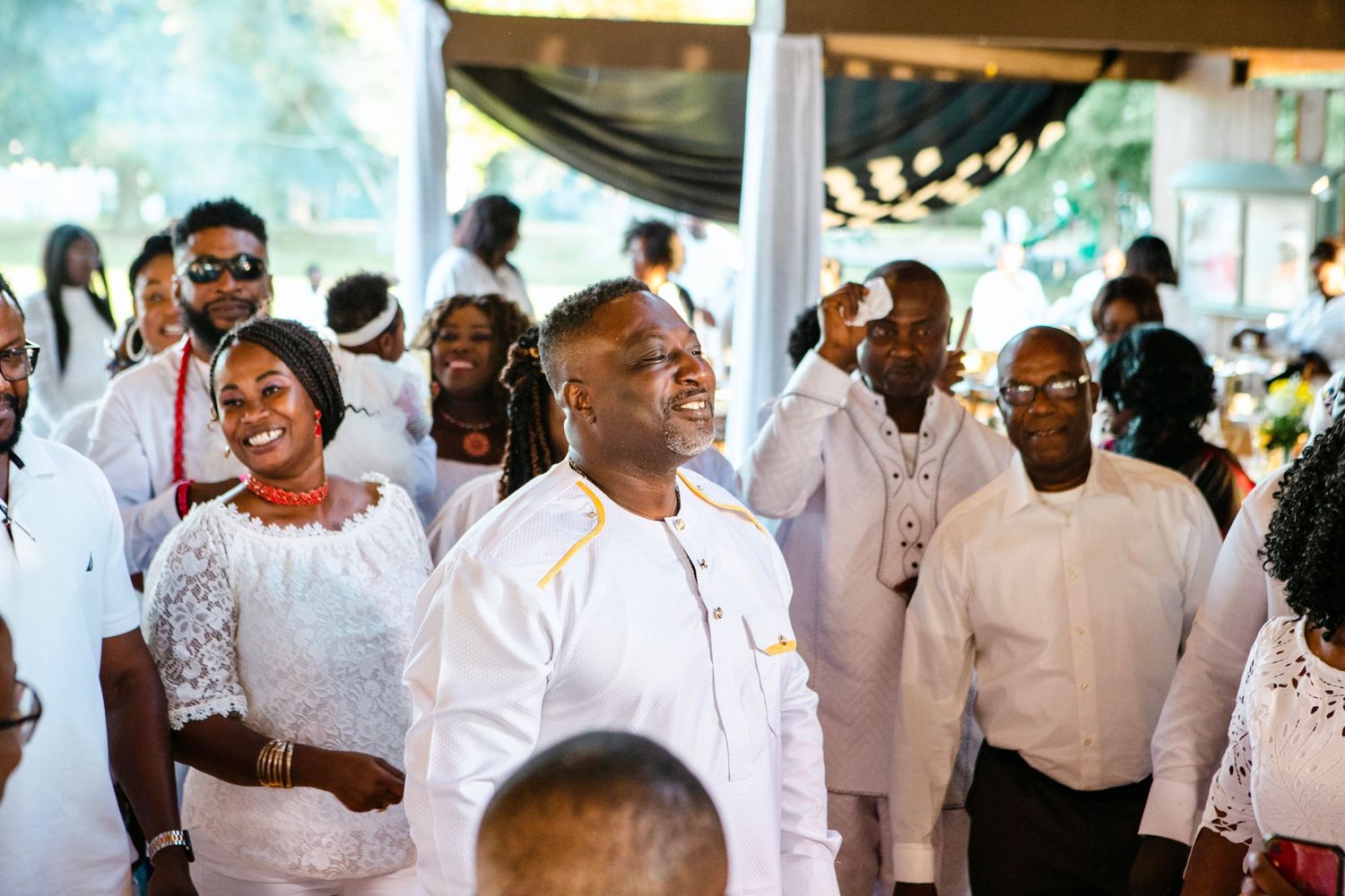Wedding reception celebration with guests in white attire dancing and enjoying themselves.