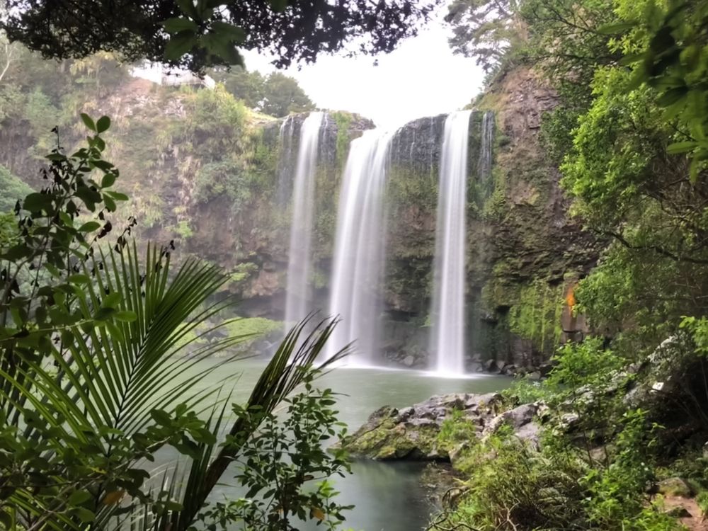 Wide waterfalls pour into a tranquil lagoon framed by lush jungle vegetation.