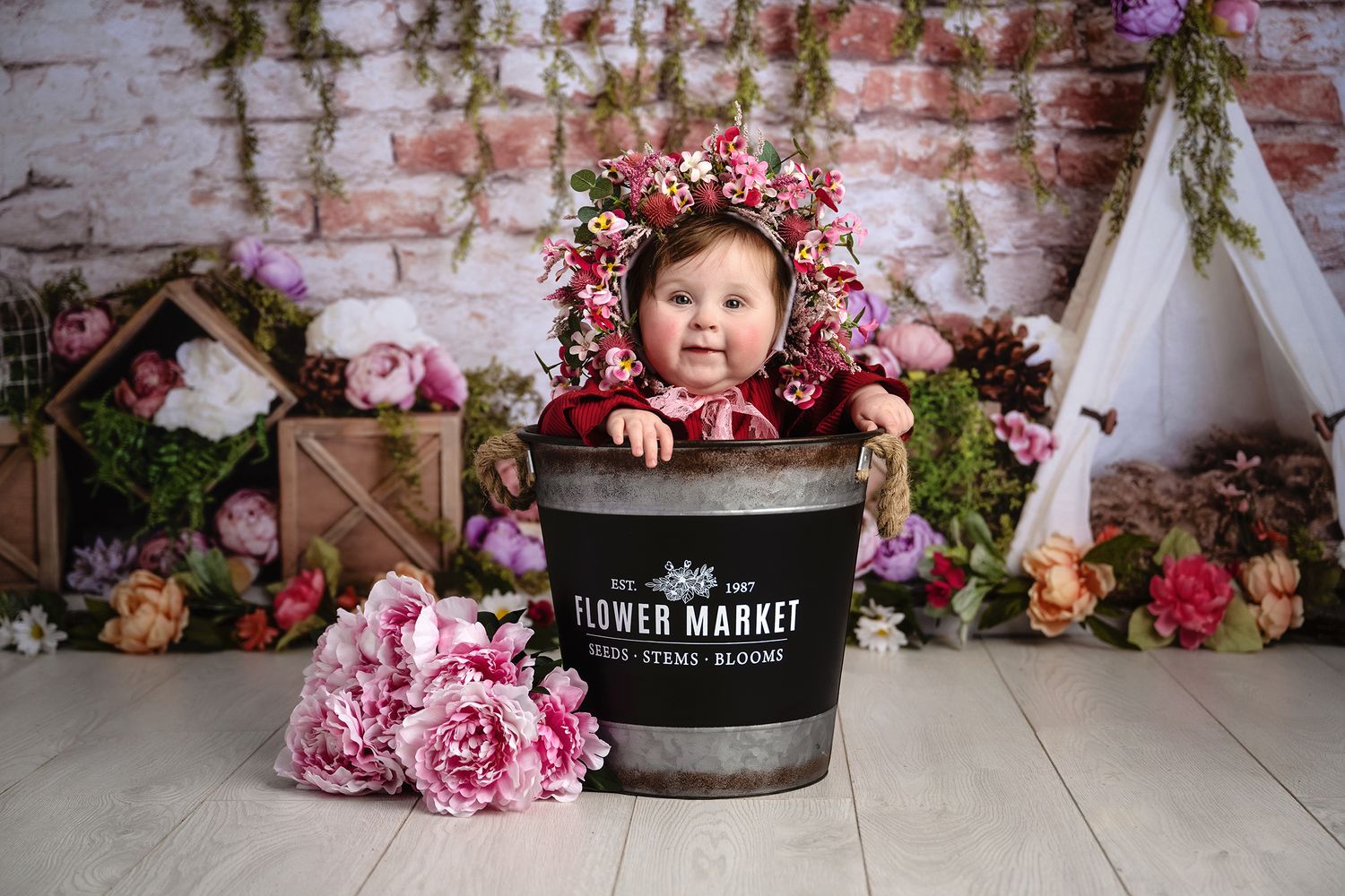 Vintage market barrel surrounded by pink flowers against brick wall creates rustic charm.