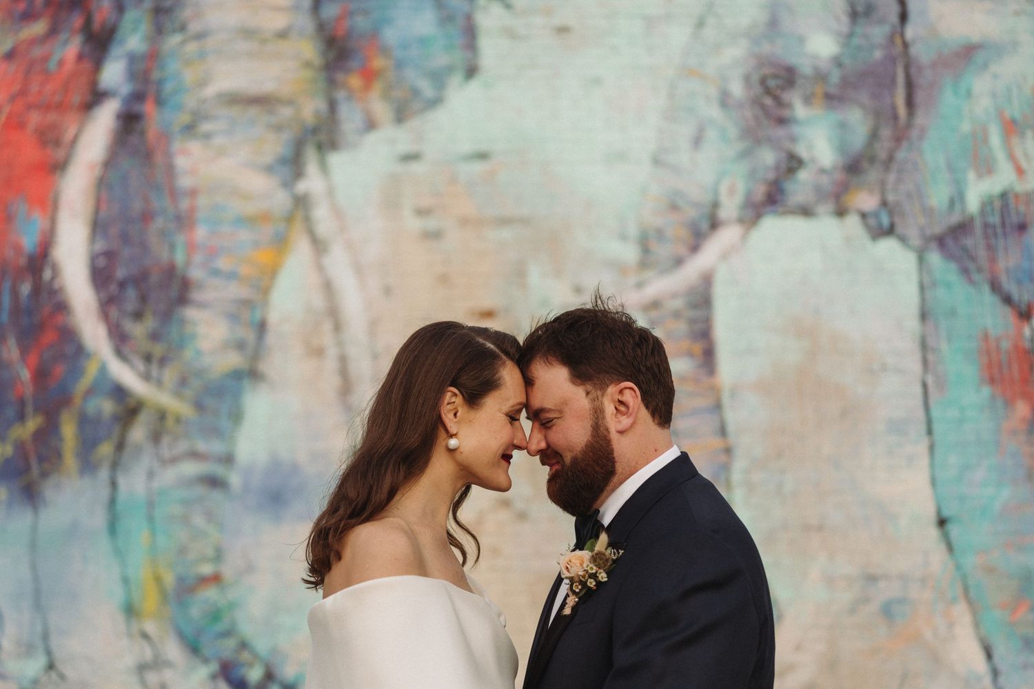 A romantic wedding portrait against a colorful abstract mural background.