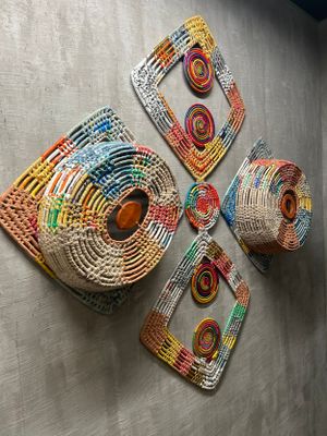 Collection of woven wall art pieces featuring geometric patterns in vibrant colors and metallic accents.