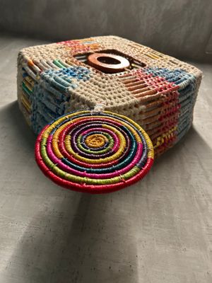 Colorful woven textile box with circular coaster featuring vibrant concentric patterns and geometric designs.