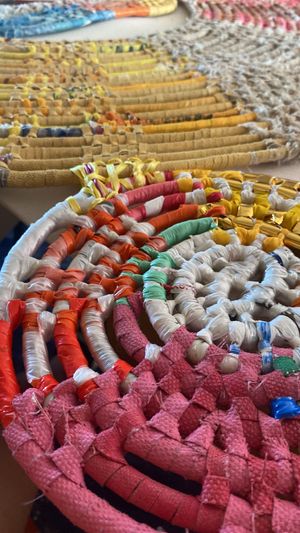 Close-up of colorful coiled rope art showing intricate woven patterns in pink, yellow, and orange.