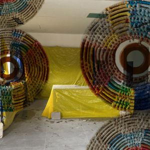 Colorful circular maze-like installation with yellow walls and geometric patterns in an indoor space.