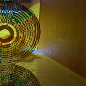 Illuminated circular bead sculpture glowing against dark wall creating dramatic lighting effects.