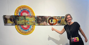 Large decorative wall sculpture made from colorful woven beads in a circular symmetric pattern.