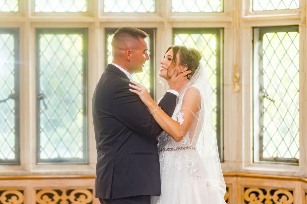 A couple shares an intimate wedding dance moment in front of a window with diamond lattice panes.