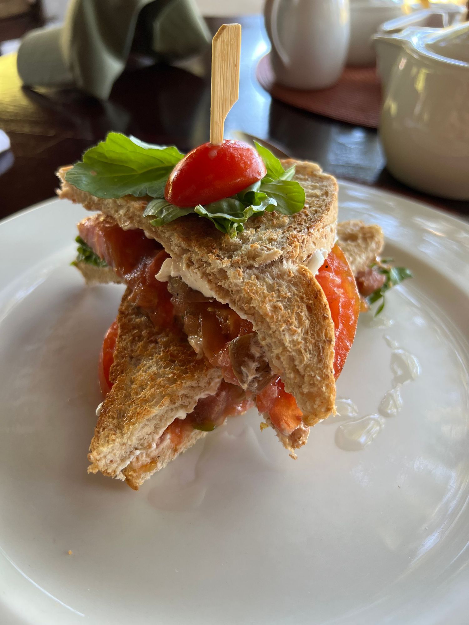 Gourmet sandwich with fresh vegetables served on a white plate.
