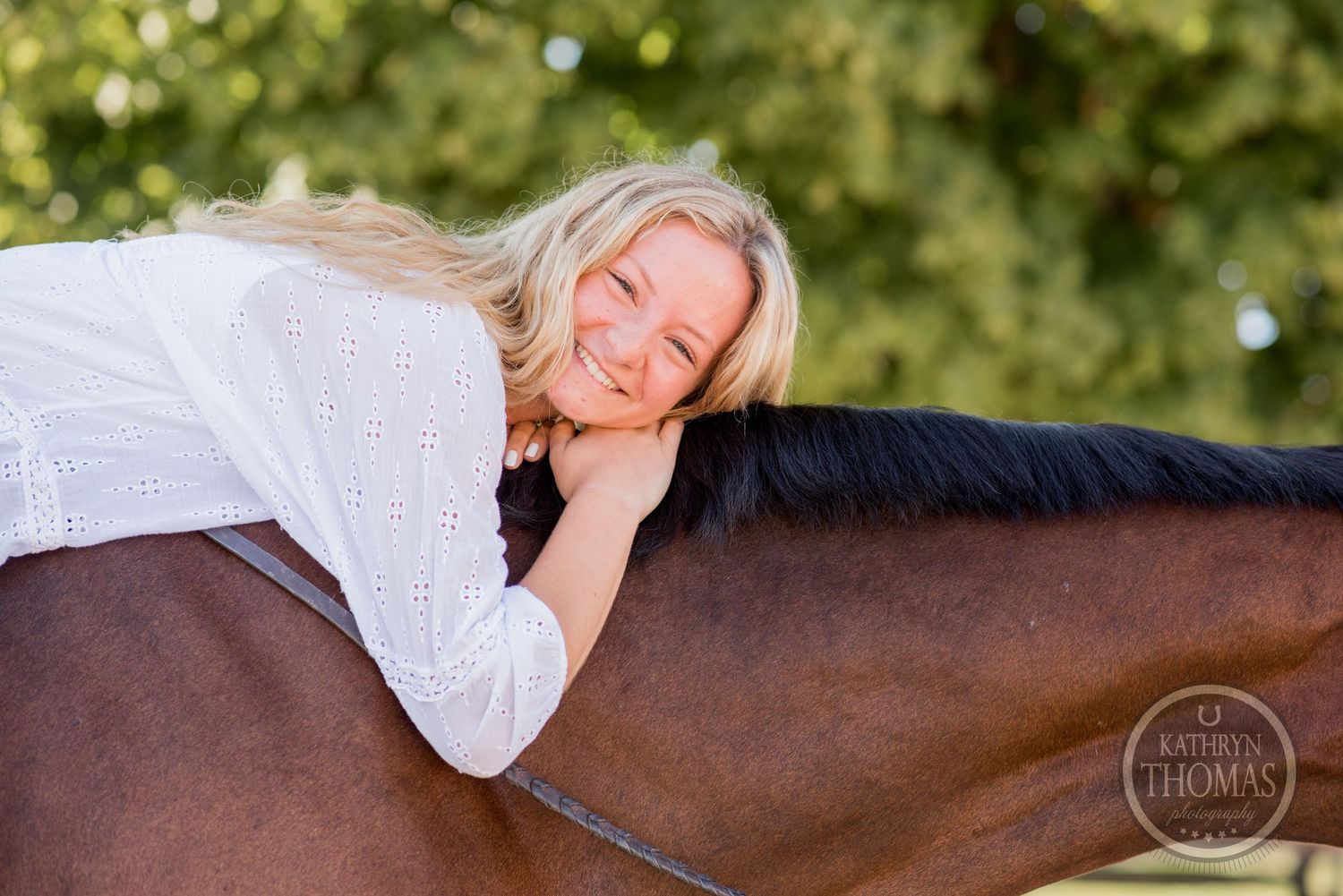 Person in white top resting peacefully on bay horse's back in sunlit outdoor setting.