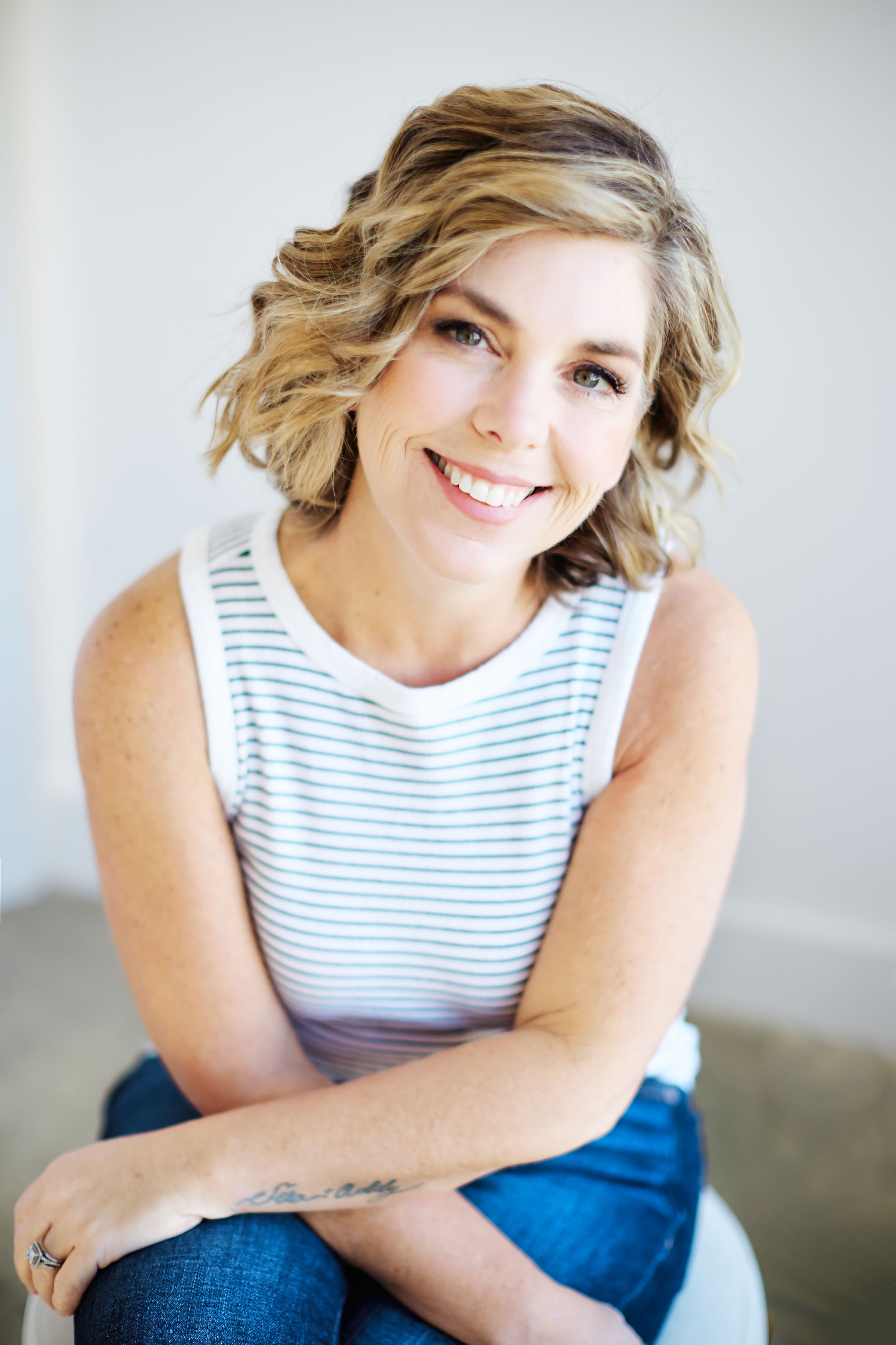 Portrait series featuring casual poses in striped top and jeans against light background.