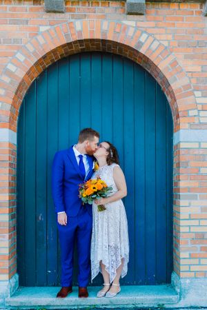 bride and groom kiss in front of milwaukee lakefront blue wall