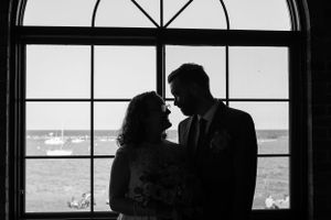 black and white silhouette of bride and groom in front of window facing lake michigan in milwaukee with boats on water