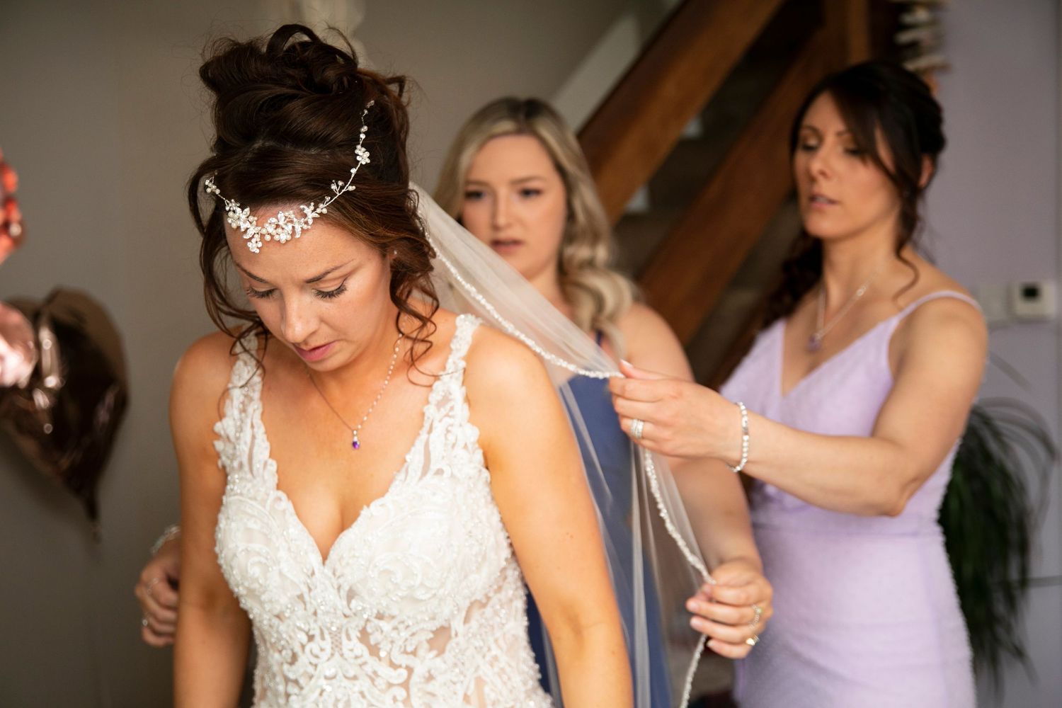 Wedding preparation scene with bridesmaids in lavender dresses helping with final touches.