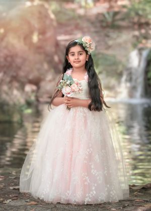 Dark haired girl standing in front of waterfall at John Oldham Park holding flowers and wearing tutu style gown.