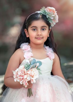 Young girl with long dark hair wearing a light pink sparkly tutu gown holding flowers