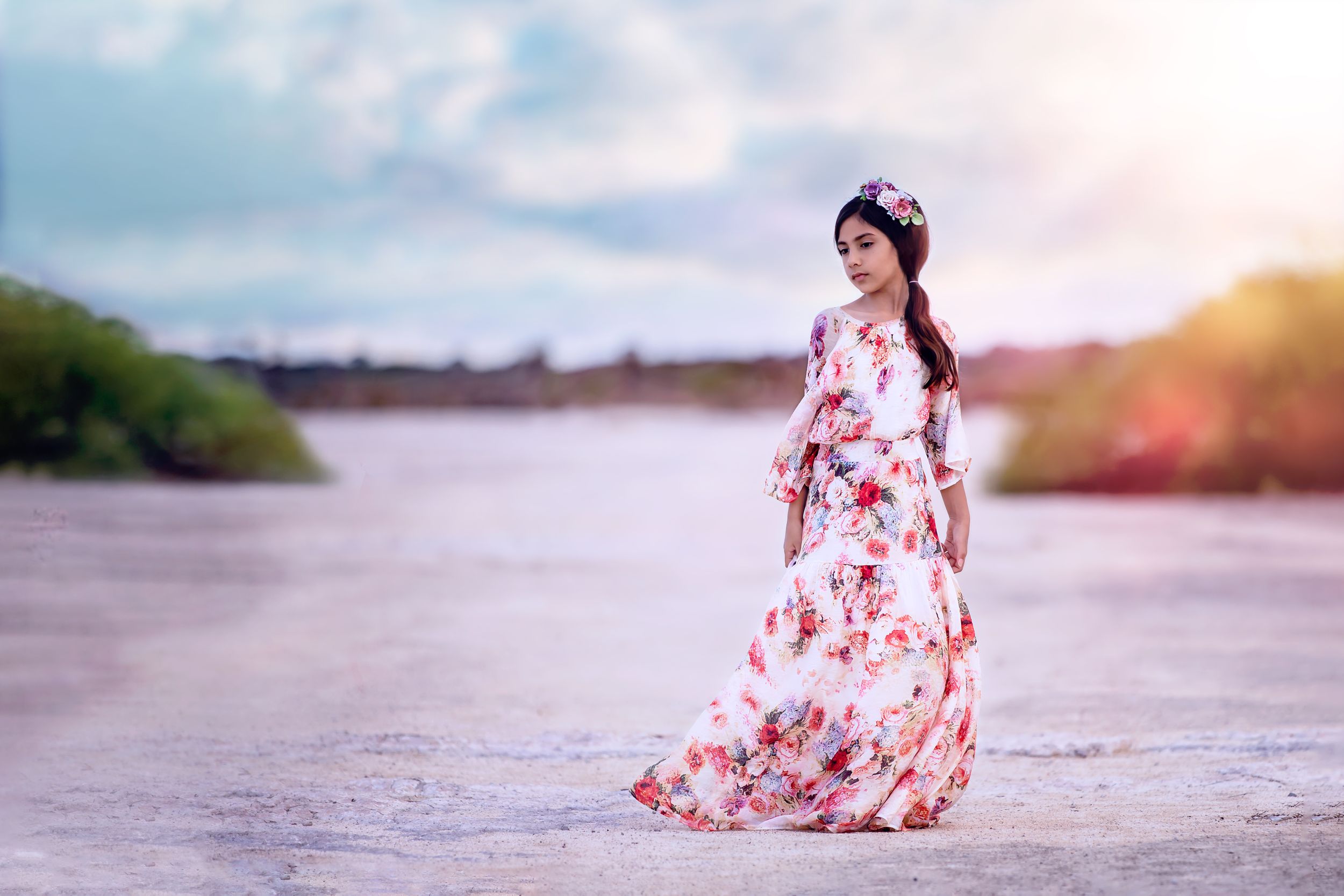 Sunset at Rockingham Salt Lakes. Young girl wearing long floral dress and floral headpiece looks wistfully away.