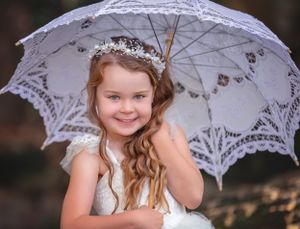 Child Portrait of girl in white gown with white beaded headband holding a white lace parasol at John Oldham Park Perth.