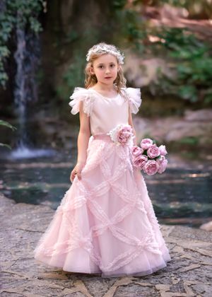 Girl in light pink couture gown holding a bouquet of flowers standing in front of waterfall at John Oldham Park Perth.