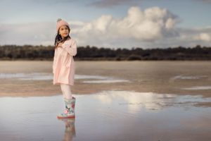 Landscape image of Rockingham Salt Lakes on a rainy day with a child in gumboots standing in a huge puddle in foreground
