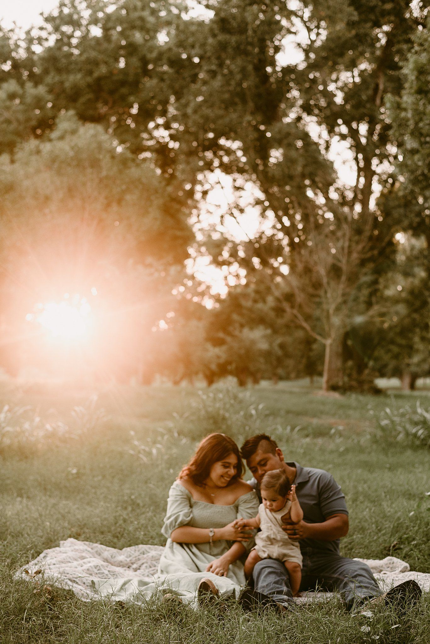 Intimate family portrait with their pet dog during golden hour in a park setting.