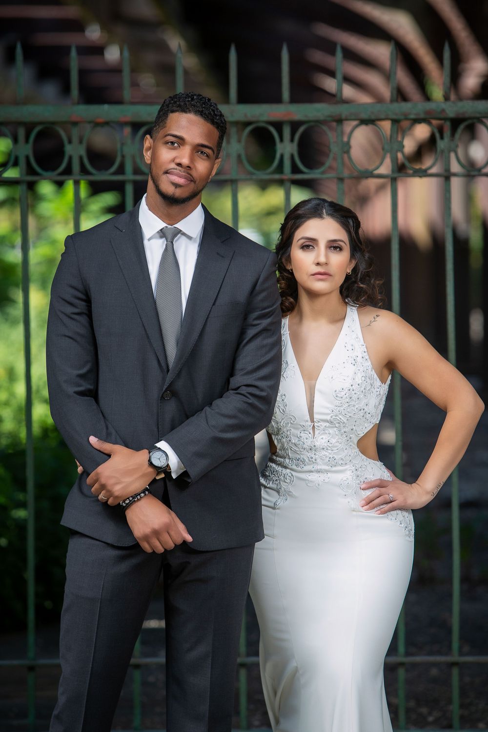 a couple pose for photos outside a gated entrance, in the style of canon eos 5d mark iv