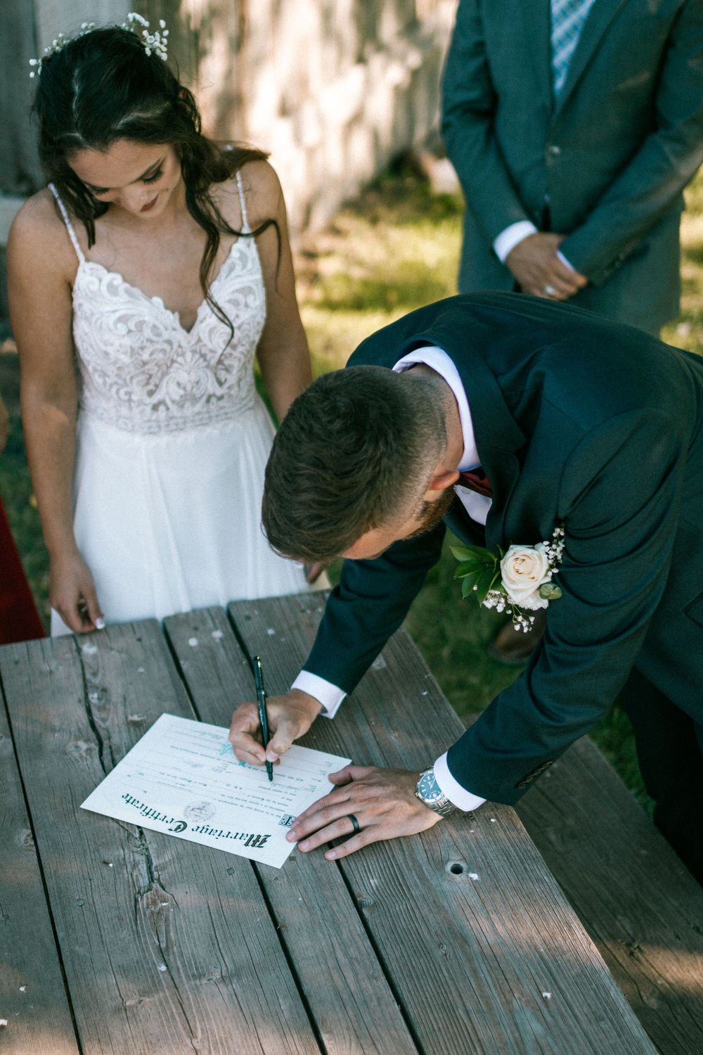 Wedding ceremony signature moment on wooden deck with couple in formal attire.