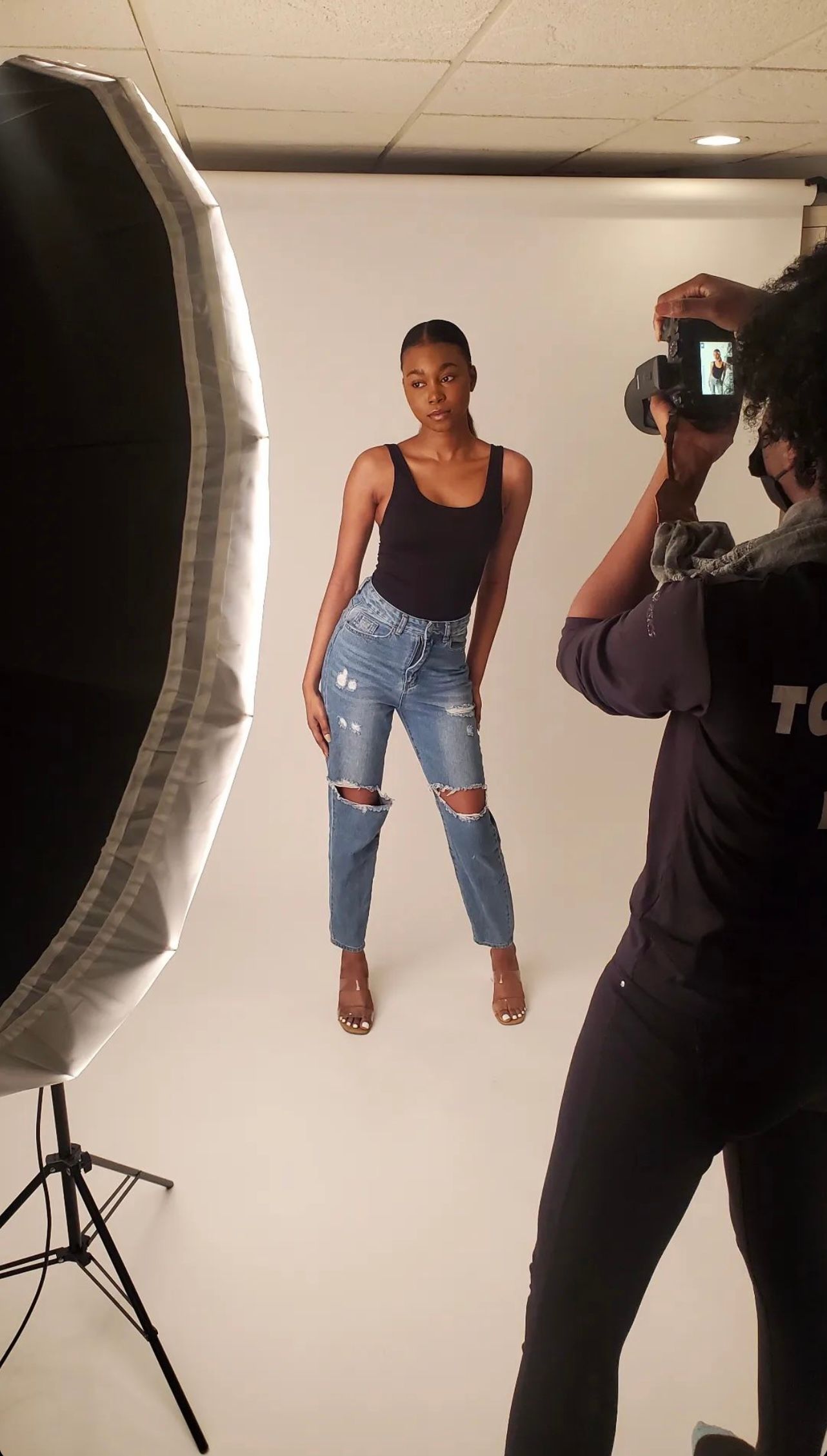Behind-the-scenes studio photoshoot with lighting equipment and photographer in action.