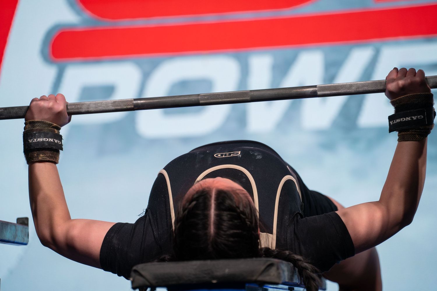 Athletes performing pull-ups on exercise bars against a bright red background.
