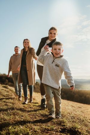 Candid family moments captured on a sunny hillside during golden hour.