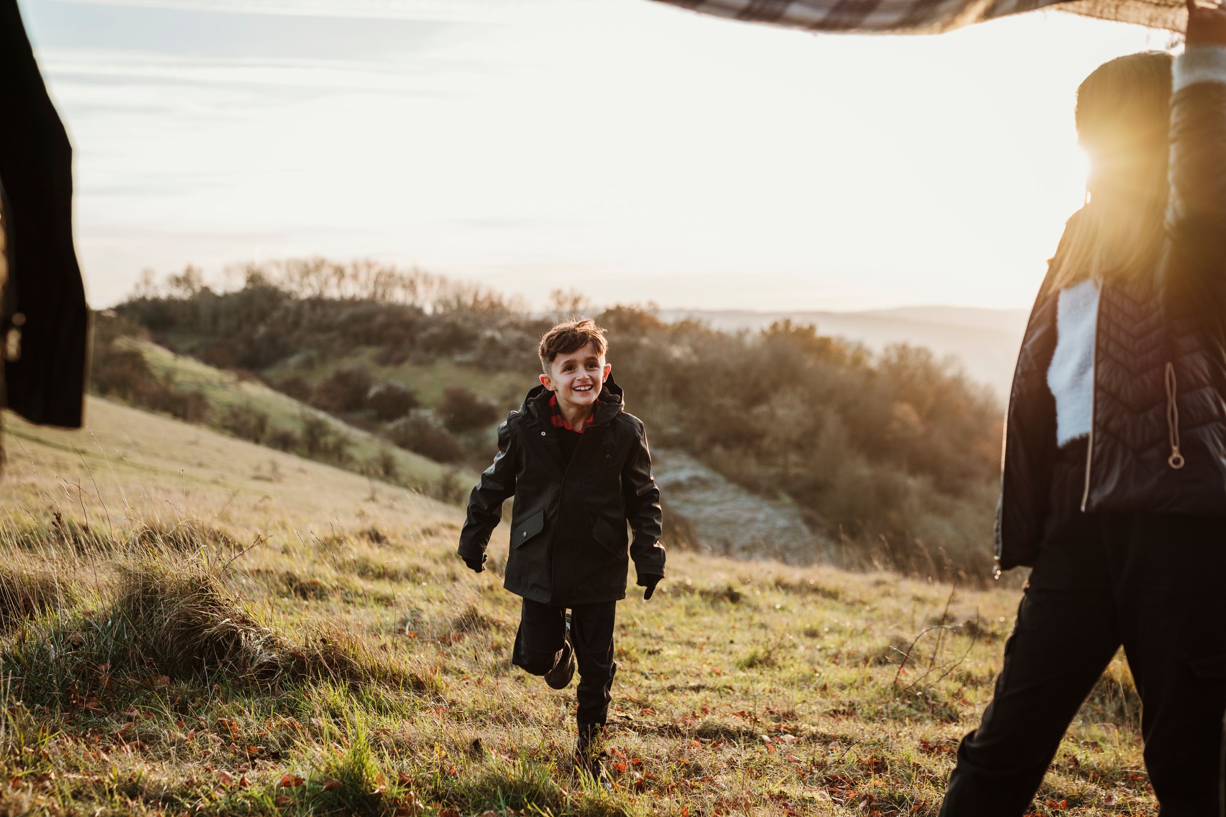 Silhouettes of family members playing together on a hill during golden hour.