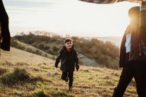 Silhouettes of family members playing together on a hill during golden hour.