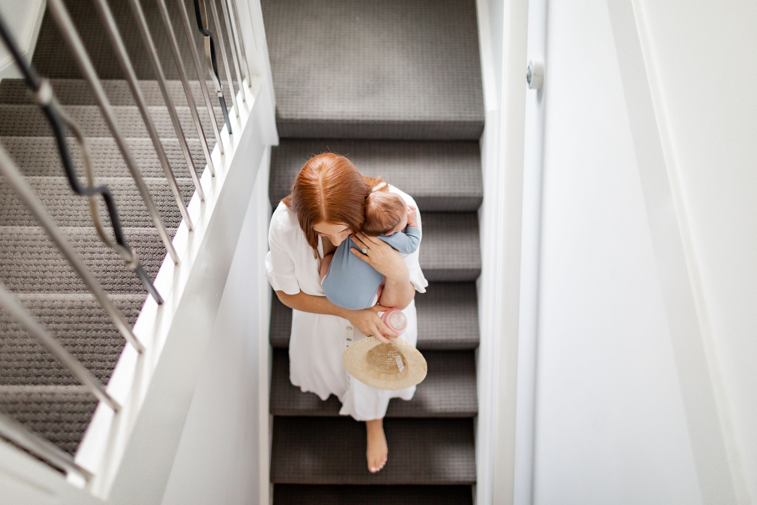 Overhead view of parent and child embracing on white staircase.