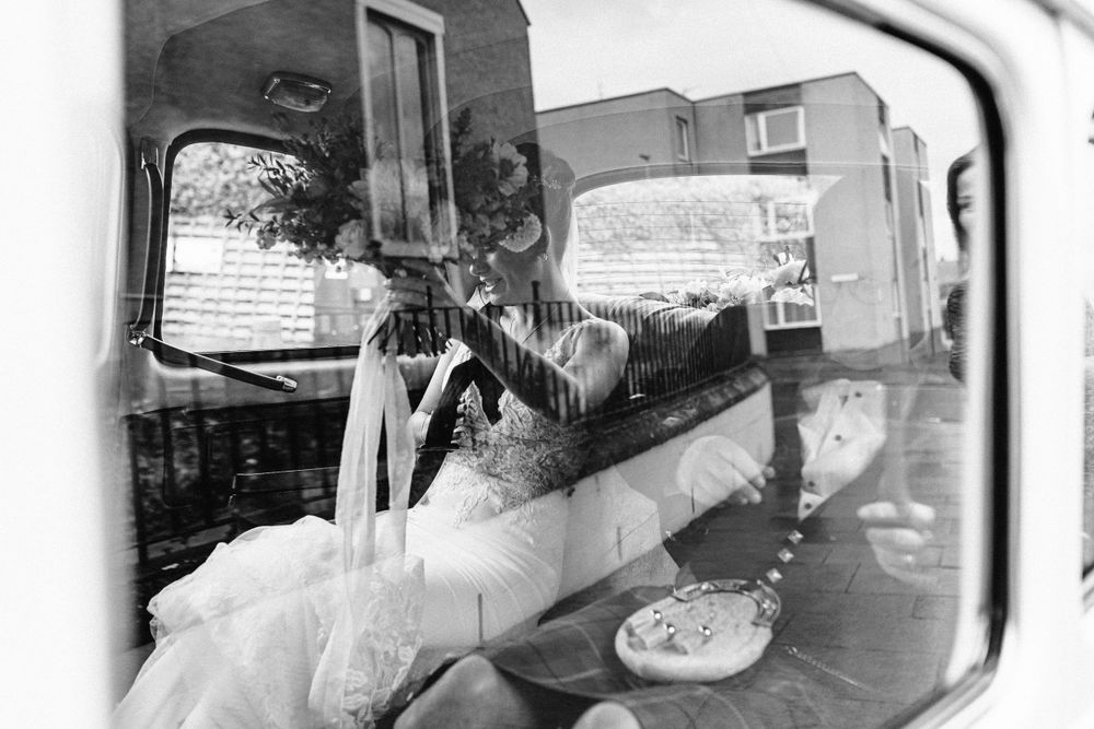 Black and white view through car window showing wedding day reflections and decorations.