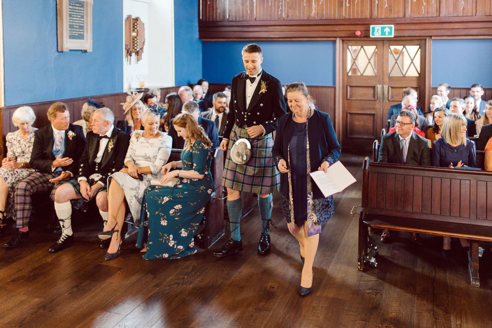 Wedding ceremony guests seated in a room with blue walls and wooden paneling.