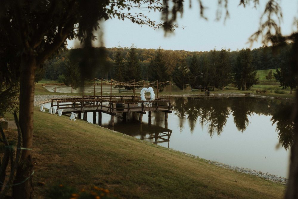Scenic lakeside dock with wedding arch reflecting in calm waters during golden hour.