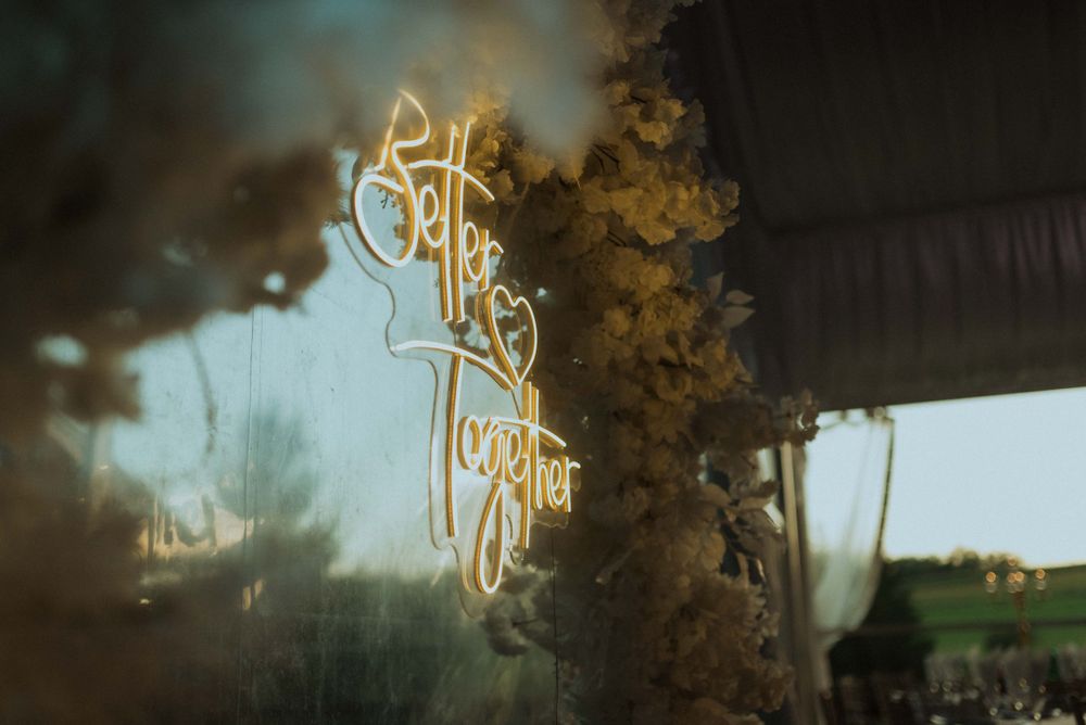Illuminated 'Better Together' neon sign with dreamy blur effect and natural backdrop.