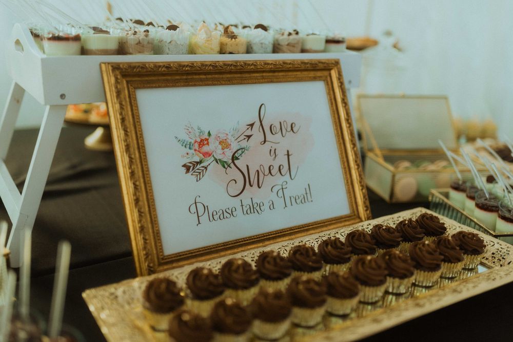 Vintage framed 'Love is Sweet' dessert table sign with chocolate treats displayed.