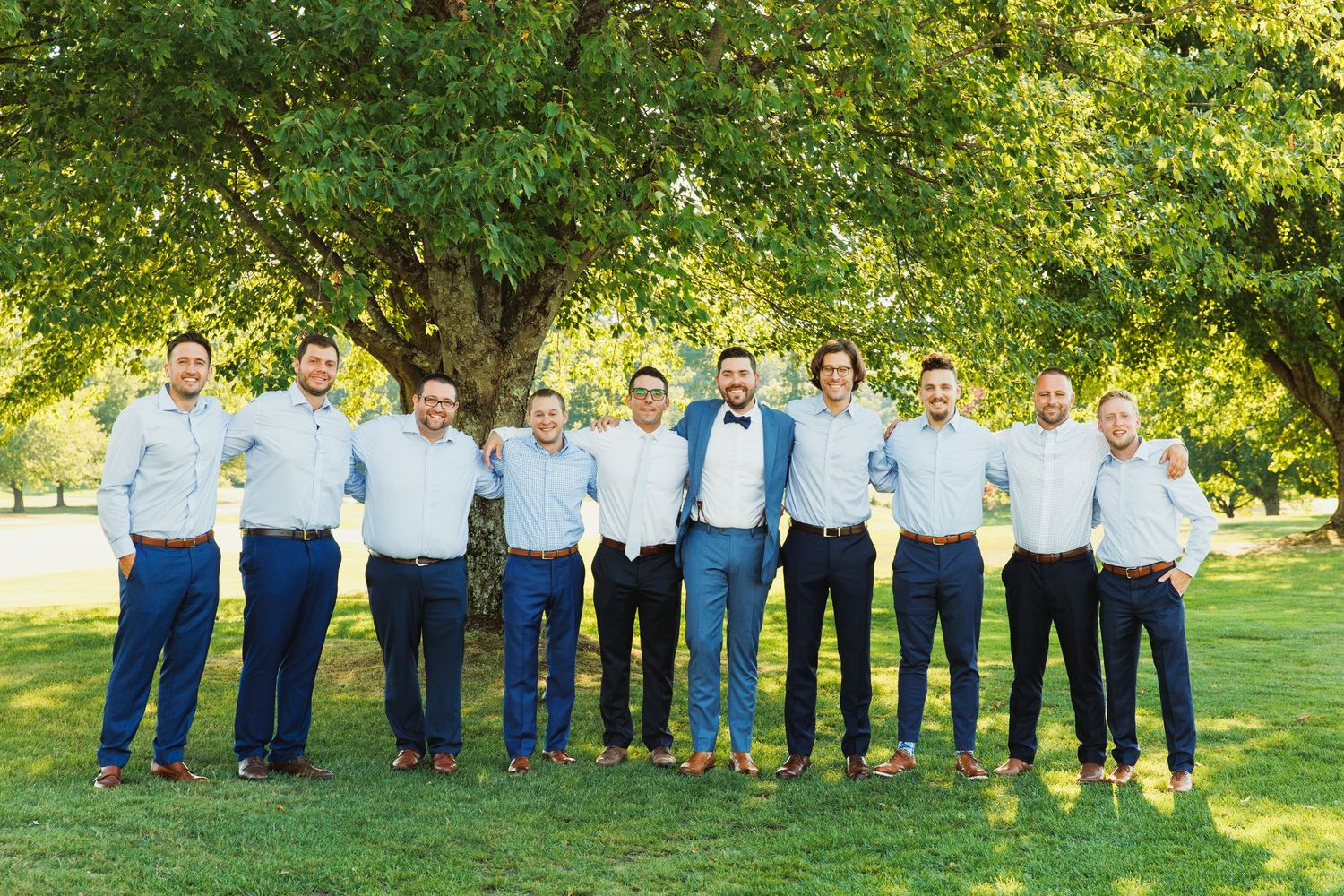 Large group photo taken on sunny green lawn with coordinated blue and white attire.