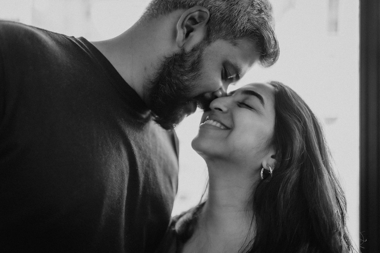 Intimate black and white portrait of couple sharing close romantic moment.