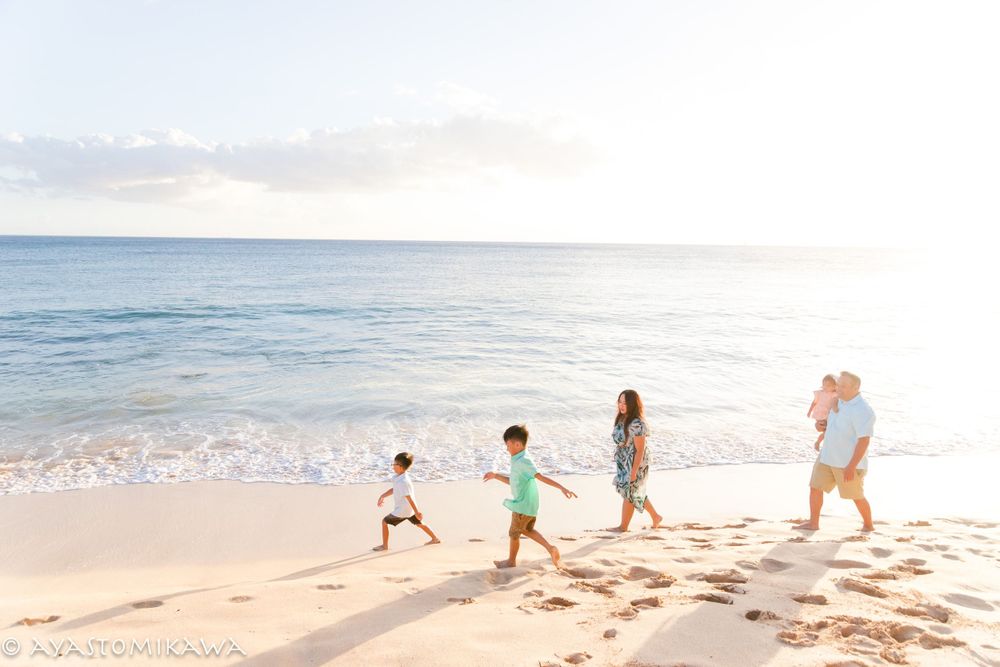 A group plays together on a sandy beach during a beautiful Hawaiian sunset.