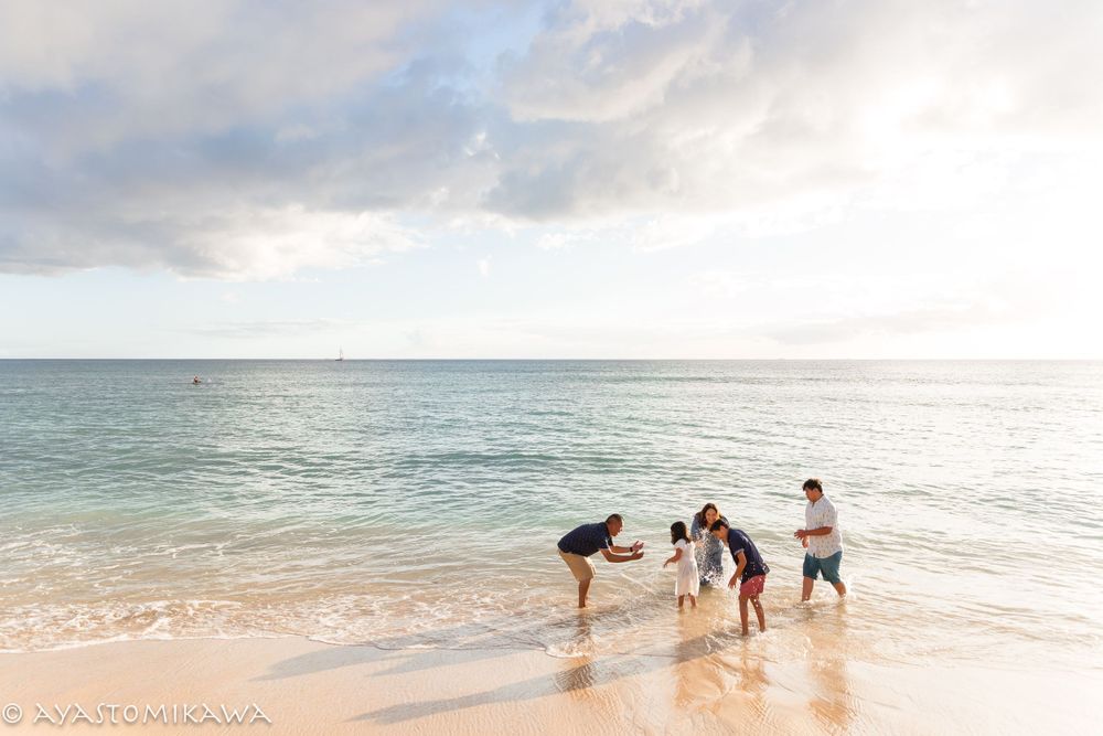 People playing and splashing together at the beach during sunset with ocean waves.