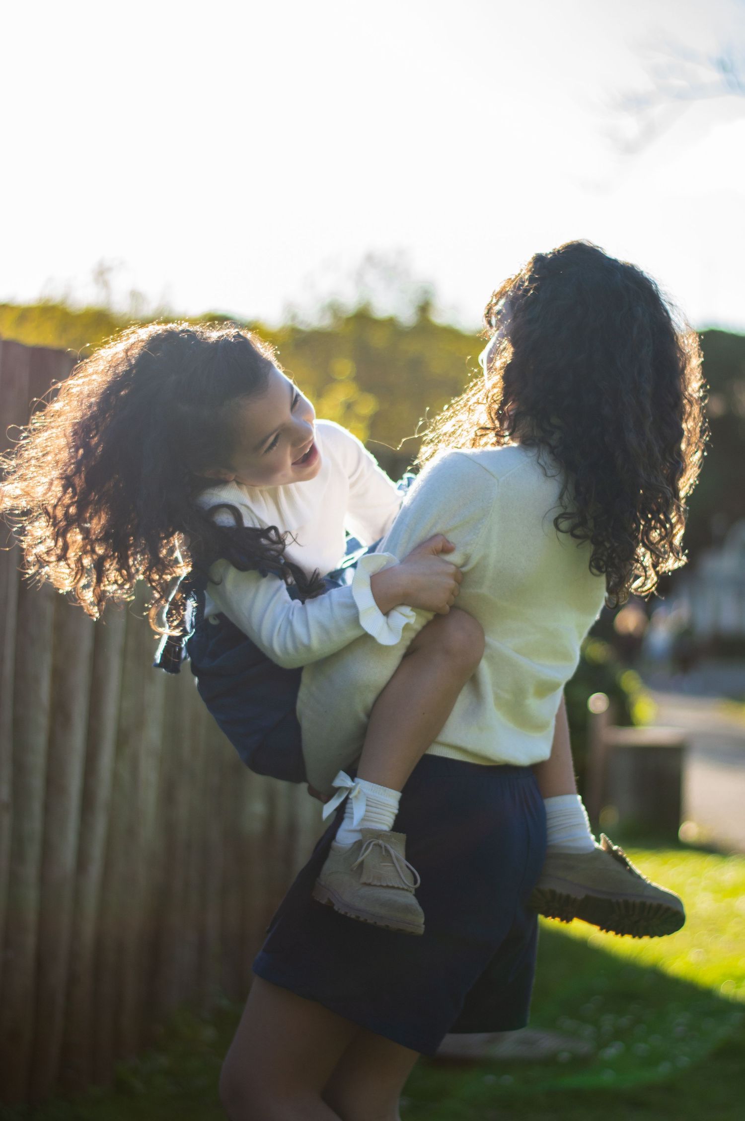 Two people sharing a joyful moment outdoors in backlit golden sunshine.